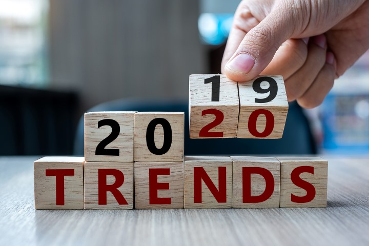 Business man hand holding wooden cube with flip over block 2019 to 2020 Trends word on table background. Resolution, strategy, solution, goal, business, New Year New You and happy holiday concepts